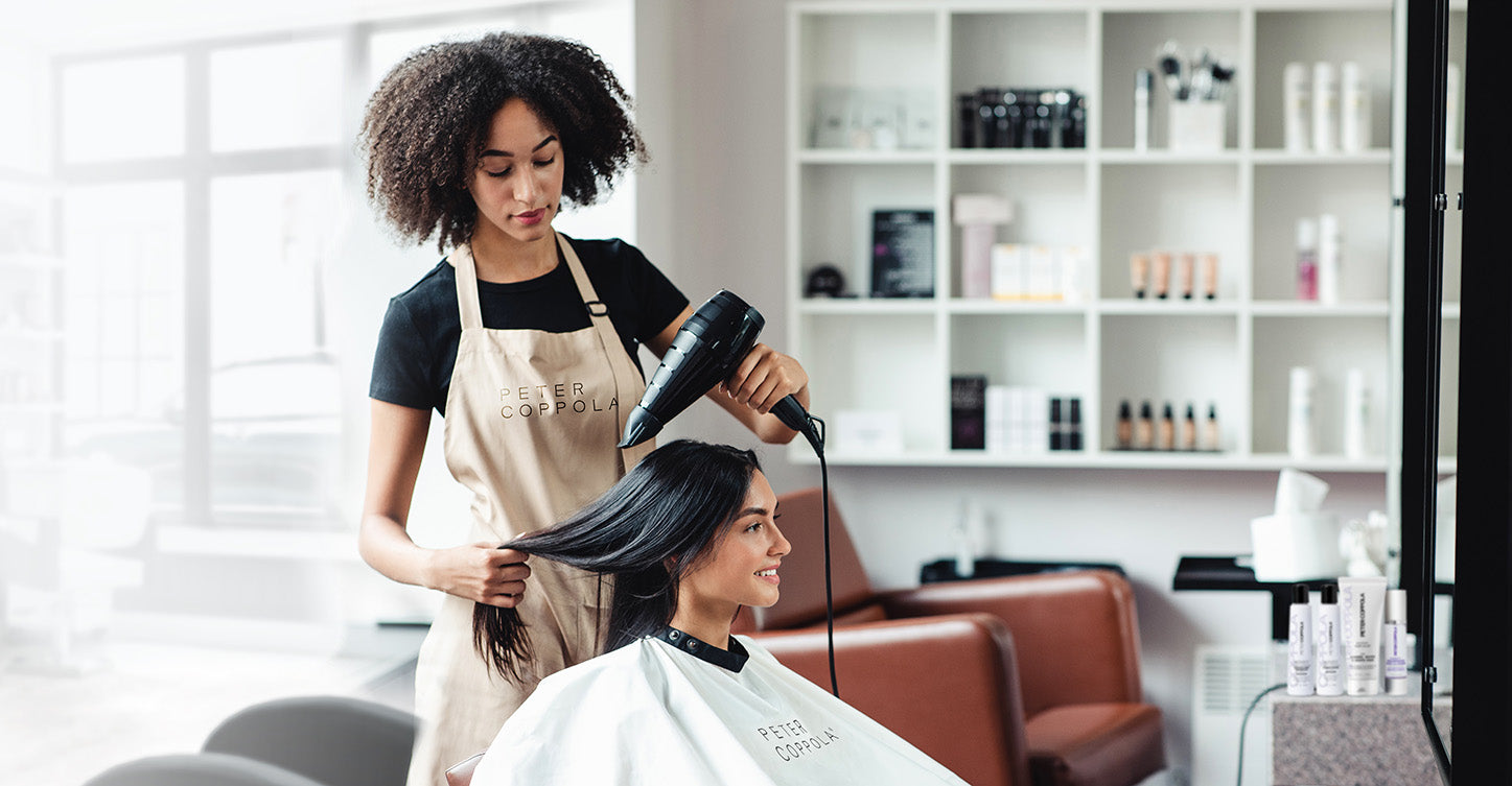 Hairstylist giving client keratin smoothing treatment while in hair salon